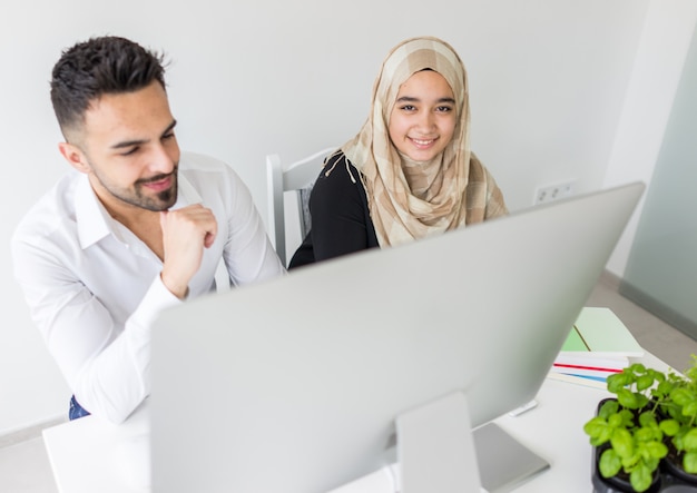 Junger mand und Frau, die im Büro auf Computer arbeitet