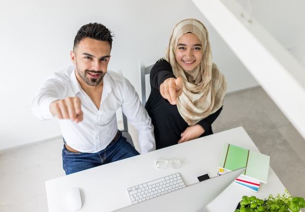 Junger mand und Frau, die im Büro auf Computer arbeitet