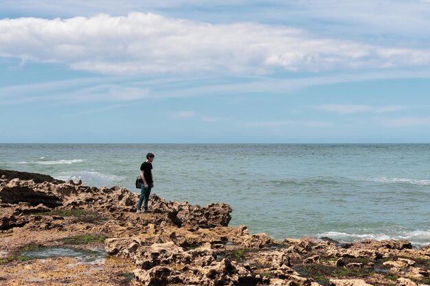 Junger Mann am felsigen Ufer der Nordsee