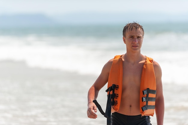 Junger Mann am Strand in einer Schwimmweste.