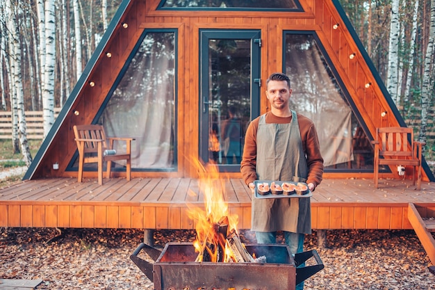 Junger Mann am warmen Tag des Herbstgrills im Freien