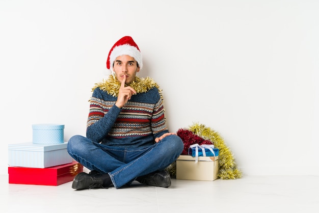 Junger Mann am Weihnachtstag, der den Spaß bedeckt Hälfte des Gesichtes mit Palme hat.