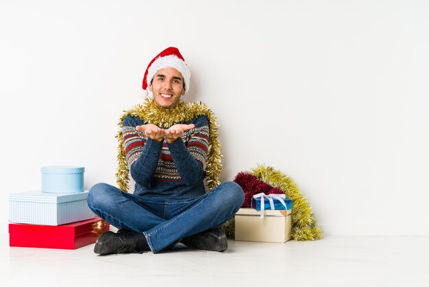 Junger Mann am Weihnachtstag lacht und schließt die Augen, fühlt sich entspannt und glücklich.