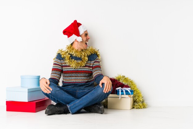 Junger Mann am Weihnachtstag lächelnd überzeugt mit den gekreuzten Armen.