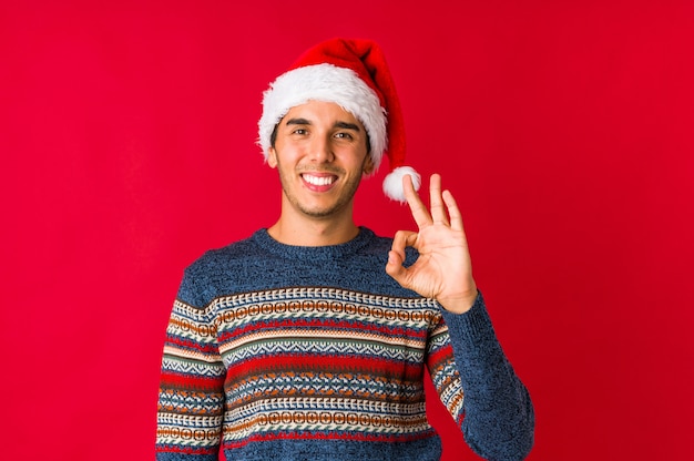 Junger Mann am Weihnachtstag macht Skala mit den Armen, fühlt sich glücklich und überzeugt.