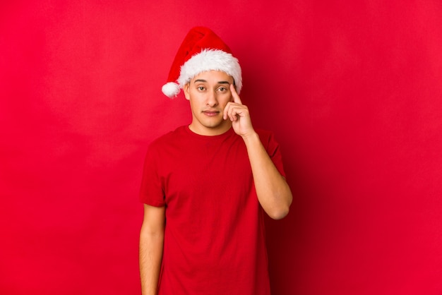 Junger Mann am Weihnachtstag Tempel mit dem Finger zeigend und denken, gerichtet auf eine Aufgabe.