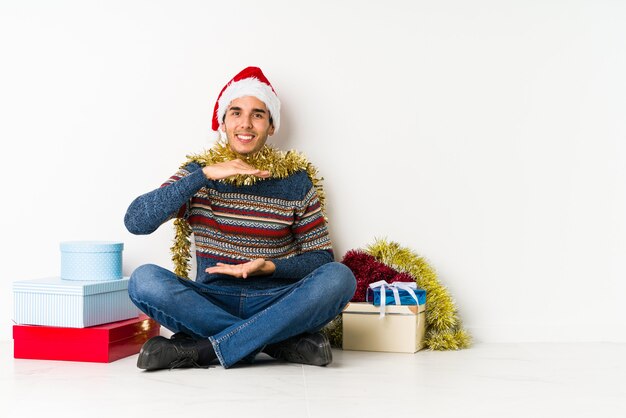 Junger Mann am Weihnachtstag zwinkert ein Auge und hält eine okaygeste mit der Hand.