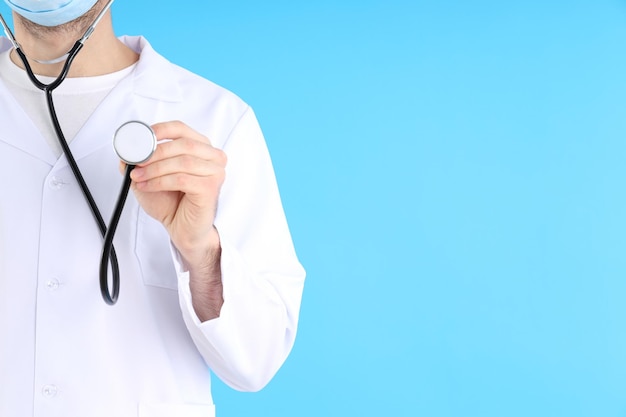 Junger Mann Arzt mit Stethoskop auf blauem Hintergrund