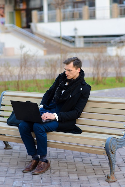 Junger Mann auf der Straße mit mobilem Computer.