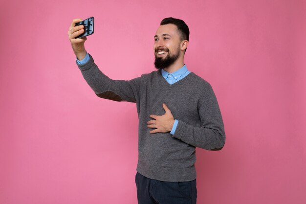 junger Mann auf einem rosa Hintergrund nimmt ein Selfie