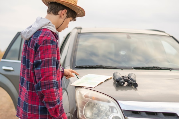 Junger Mann auf einer Autoreise mit dem Auto unter Verwendung des Fernglases und suchen den Weg