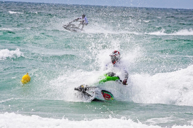 Junger Mann auf Jet-Ski Professioneller Jet-Ski-Fahrer Jet-Ski-Meisterschaft Jetski führt viele Tricks auf den Wellen durch