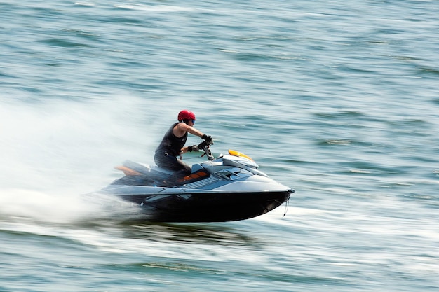 Junger Mann auf Jet-Ski Professioneller Jet-Ski-Fahrer Jet-Ski-Meisterschaft Jetski führt viele Tricks auf den Wellen durch