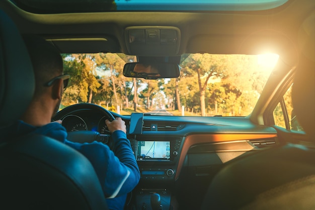 Junger Mann Autofahren bei Sonnenuntergang Mann verwendet Navigationssystem beim Autofahren