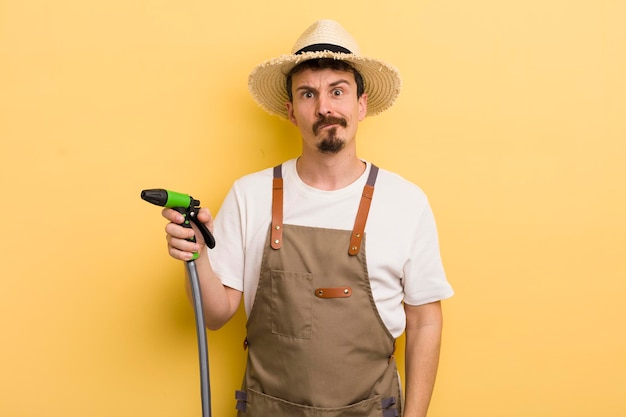 Junger Mann Bauer mit einem Schlauchgartenkonzept