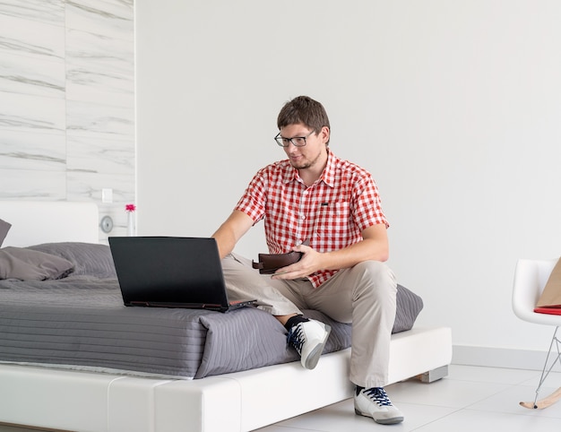 Junger Mann beim Einkaufen im Internet mit Laptop