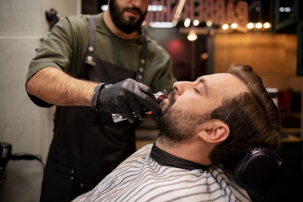 Foto junger mann beim friseur, der sich den bart schneiden lässt