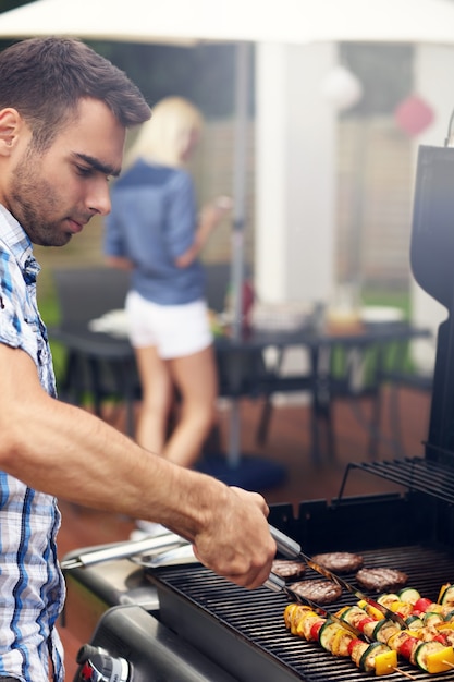 junger Mann beim Grillen von Speisen