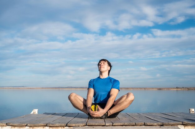 Junger Mann beim Yoga inmitten eines Sees