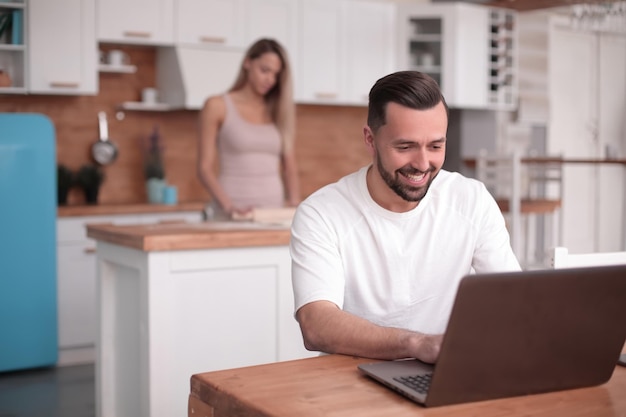 Junger Mann benutzt Laptop in der heimischen Küche