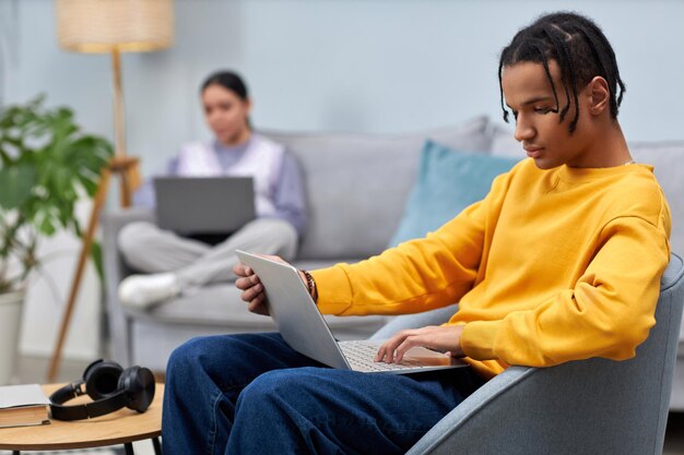 Junger Mann benutzt Laptop, während er auf dem Sofa im Büro-Lounge sitzt