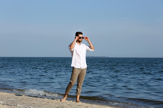 Junger Mann, der am Strand geht