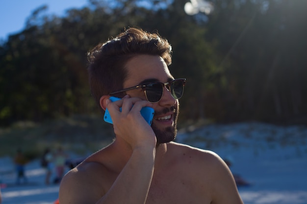 junger Mann, der am Telefon im Strand spricht