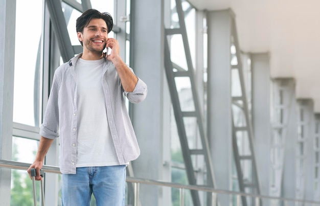 Junger Mann, der am Telefon spricht und ein Taxi zum Flughafen reserviert