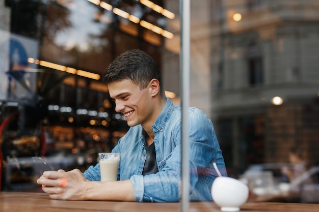 Junger Mann, der am Tisch im Café sitzt