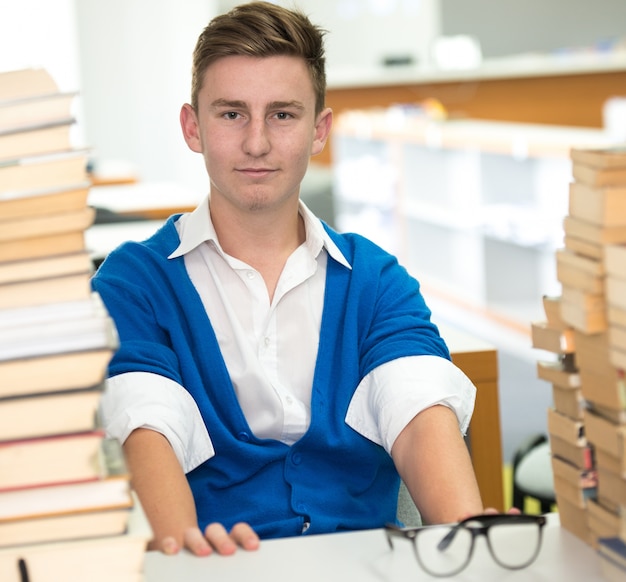 Junger Mann, der an der Collegebibliothek styling ist