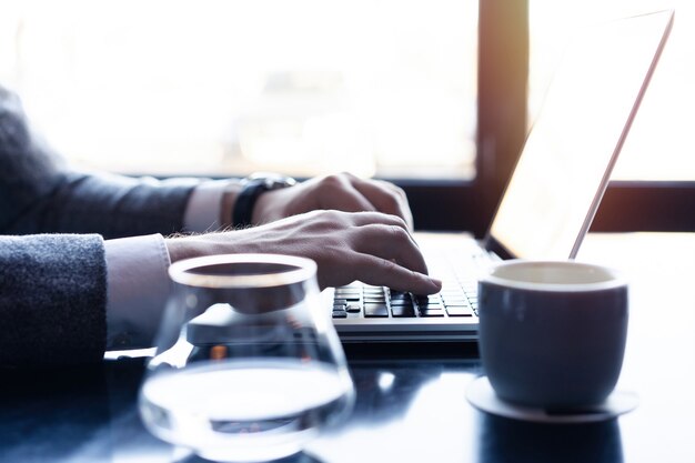 Junger Mann, der an seinem Laptop in einem Café arbeitet