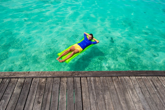 Junger Mann, der auf aufblasbarer Matratze im Meer sich entspannt