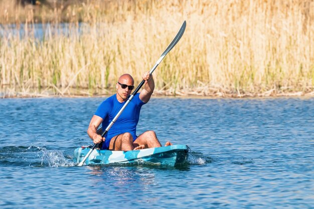 Junger Mann, der auf dem See Kajak fährt. Kajakfahren auf dem See.