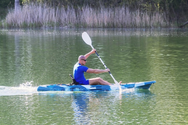 Junger Mann, der auf dem See Kajak fährt. Kajakfahren auf dem See.