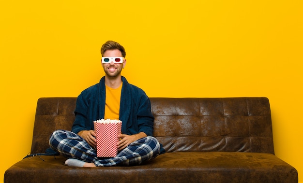 Foto junger mann, der auf einem sofa mit popcorn sitzt. kino