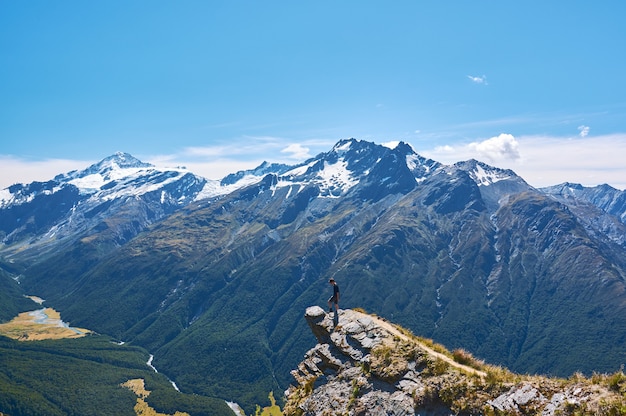 Junger Mann, der auf einer Klippe steht, die über das Tal in Neuseeland schaut