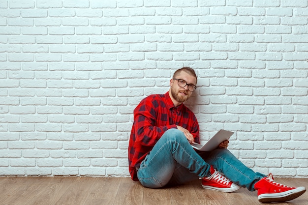 Foto junger mann, der auf fußboden mit laptop sitzt