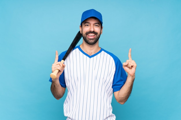 Junger Mann, der Baseball über dem lokalisierten blauen Hintergrund zeigt oben eine großartige Idee spielt