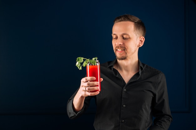 Junger Mann, der Bloody Mary Cocktail mit Sellerie hält