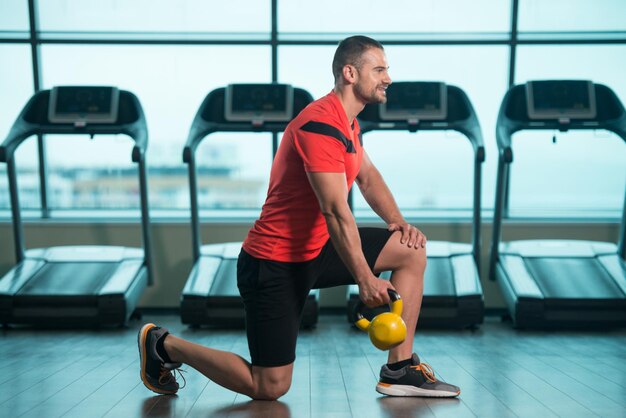 Junger Mann, der Übung mit Kettle Bell in der Turnhalle tut