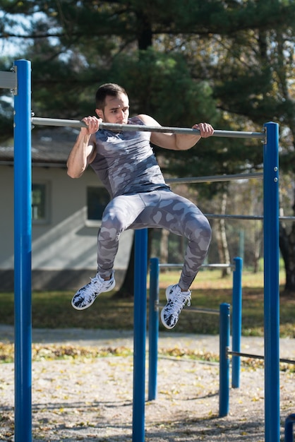 Junger Mann, der Crossfit-Übungen mit Dips-Bar im Stadtparkbereich macht Training und Training für ein gesundes Ausdauerkonzept im Freien