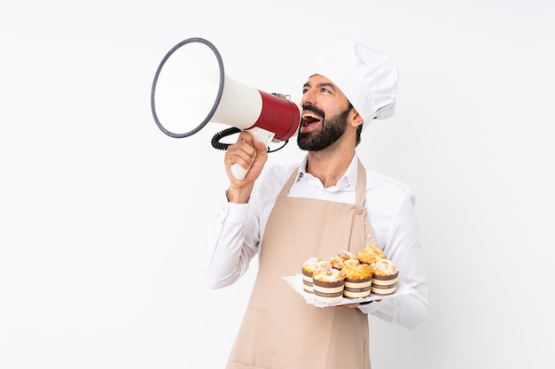 Junger Mann, der den Muffinkuchen schreit durch ein Megaphon hält