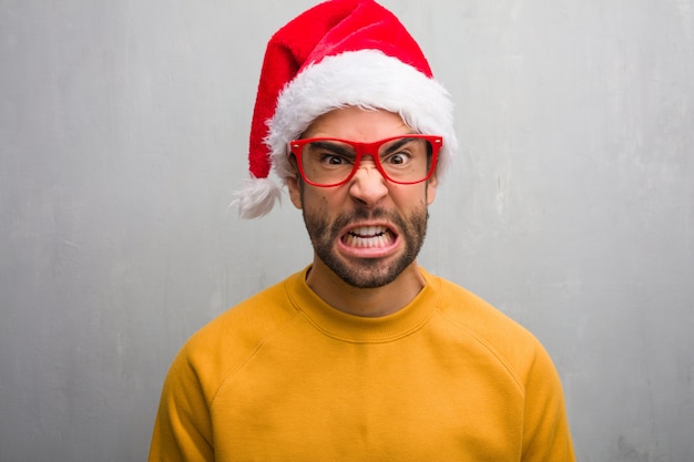 Junger Mann, der den Weihnachtstag hält die Geschenke halten feiert, die sehr verärgert und aggressiv schreien