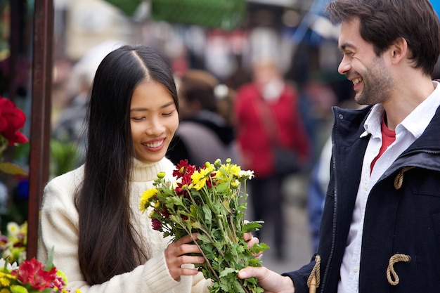 Junger Mann, der der Schönheit Blumen gibt