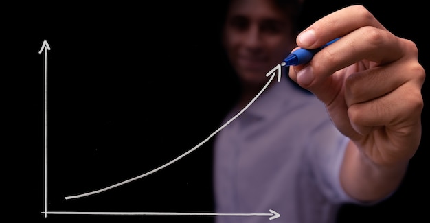 Foto junger mann, der diagramm des leistungsumsatzwachstums zeichnet. positive erwartungen für das neue jahr