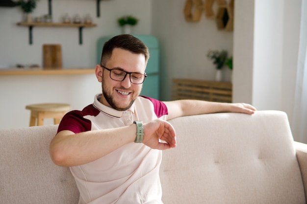 Junger Mann, der die intelligente Uhr auf einem Trainer nach dem Training betrachtet