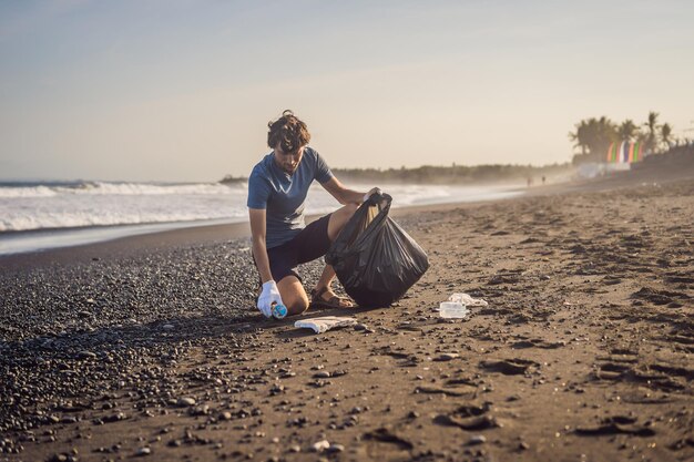 Junger Mann, der die natürliche Erziehung des Strandes von Kindern aufräumt