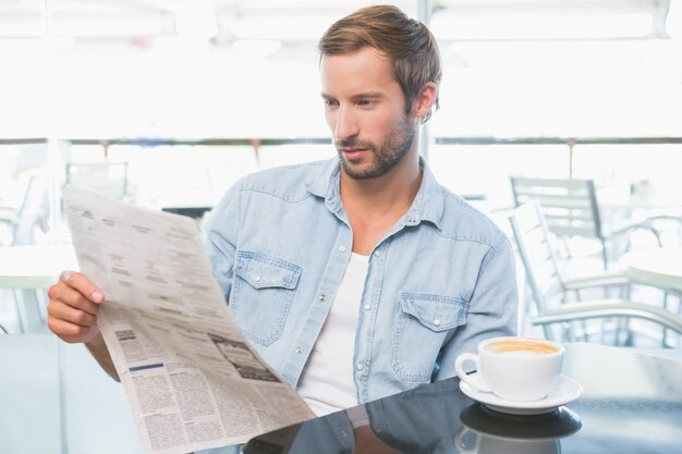 Junger Mann, der die Zeitungen liest