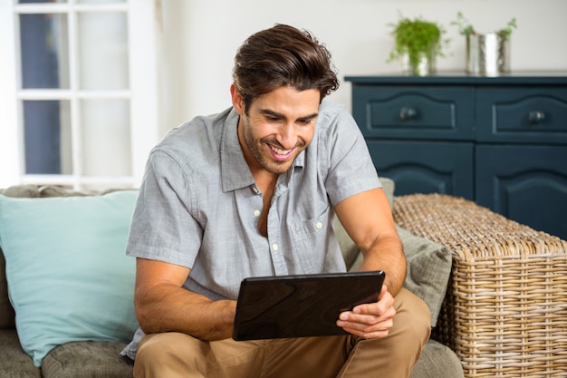 Junger Mann, der digitale Tablette im Wohnzimmer verwendet