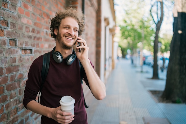 Junger Mann, der draußen am Telefon spricht.